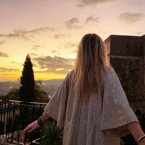 Femme de dos regardant un soleil couchant au-dessus les trois de la médina millénaire de Fès.