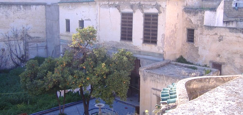 Mayfez before refurbishment. View of a badly damaged facade and lush garden